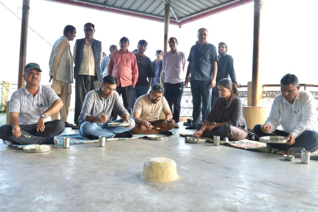 DM Savin Bansal eating food with disaster affected villagers in Dehradun