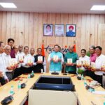 मुख्यमंत्री पुष्कर सिंह धामी पूर्व अपर सचिव आरसी लोहनी की पुस्तक सेवा विधि का विमोचन करते हुए